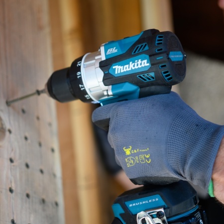 Person using a cordless Makita drill for construction work on a wooden structure.